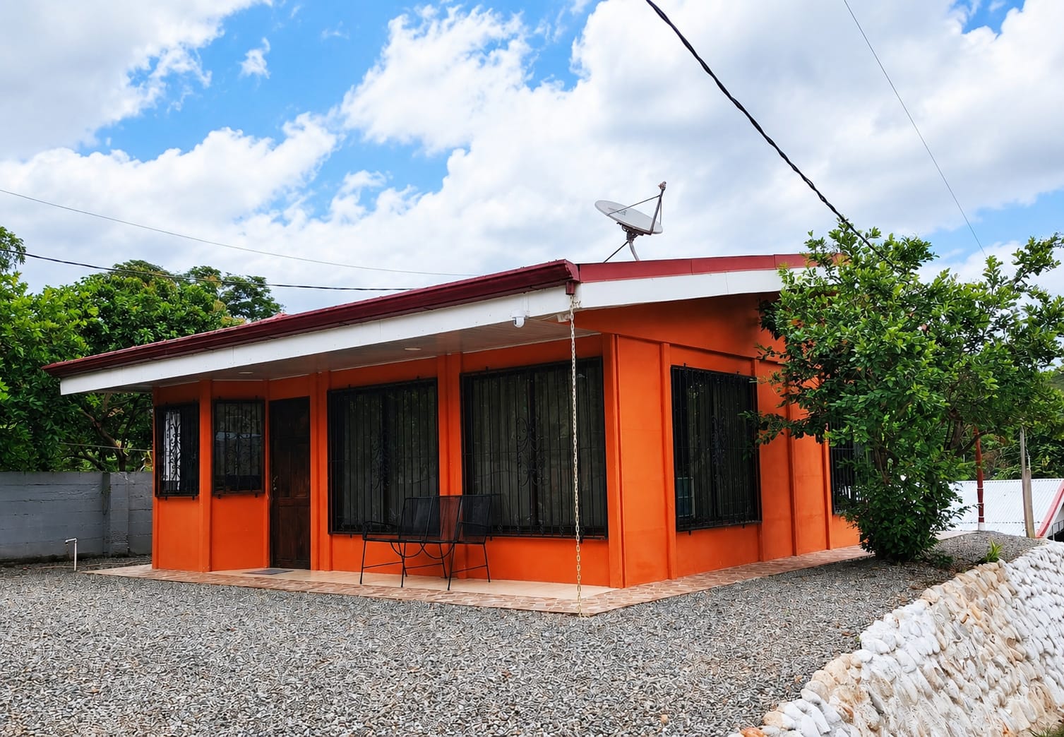 Fachada principal de casa prefabricada color naranja con ventanas y rejas negras, Pérez Zeledón